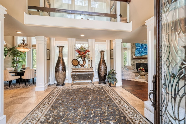 foyer featuring ornate columns, a high ceiling, and a healthy amount of sunlight