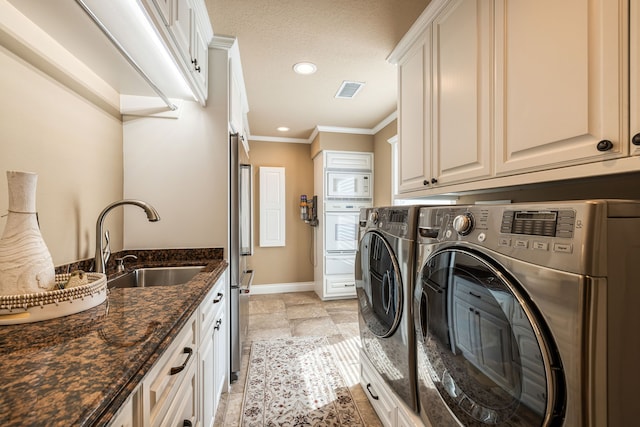 washroom with cabinets, a textured ceiling, sink, crown molding, and washer and clothes dryer