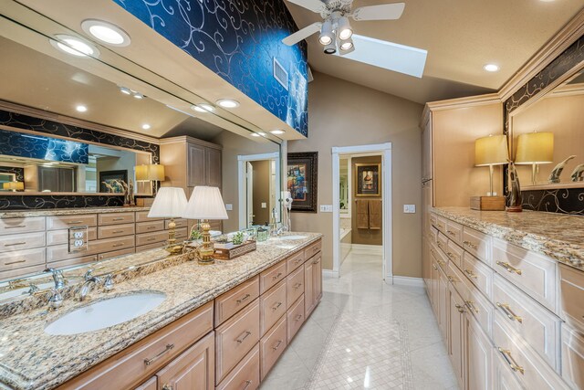 bathroom featuring lofted ceiling with skylight, vanity, ceiling fan, and tile patterned floors