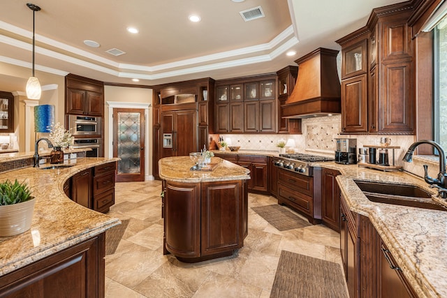 kitchen with a healthy amount of sunlight, premium range hood, sink, and pendant lighting