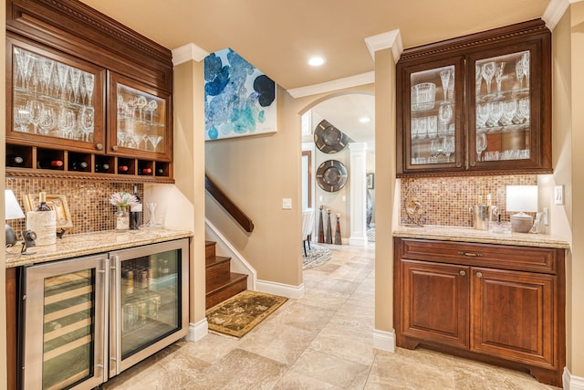 bar featuring light stone countertops, tasteful backsplash, and crown molding