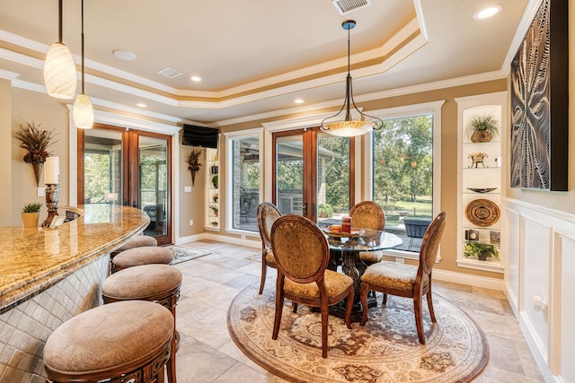 dining space with a raised ceiling, ornamental molding, and french doors