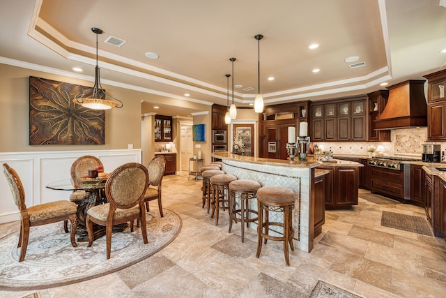 kitchen featuring a raised ceiling, a kitchen island, pendant lighting, and custom exhaust hood