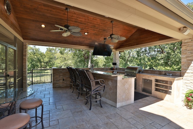 view of patio / terrace with an outdoor bar, area for grilling, ceiling fan, and an outdoor kitchen