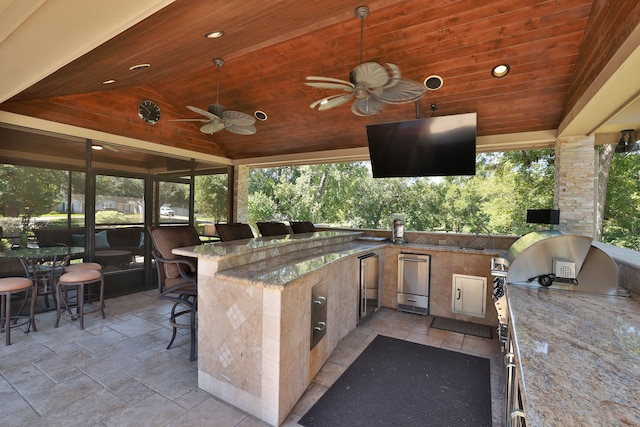 view of patio / terrace with ceiling fan, grilling area, a bar, and exterior kitchen