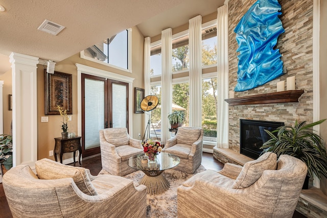 living room with a textured ceiling, a fireplace, french doors, and ornate columns