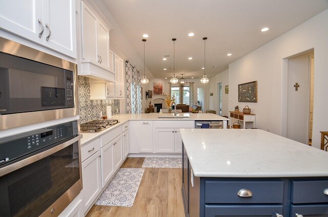 kitchen featuring light wood-type flooring, sink, white cabinets, stainless steel appliances, and blue cabinets