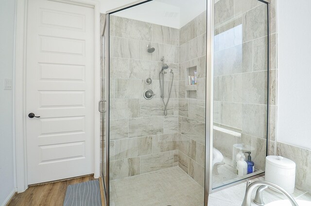 bathroom with hardwood / wood-style flooring, tile walls, and a shower with door