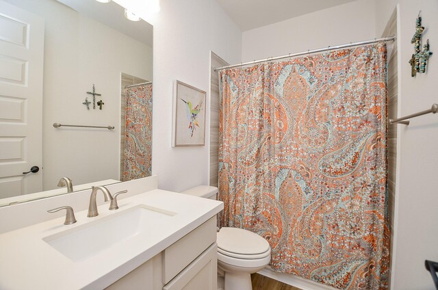 bathroom featuring a shower with shower curtain, hardwood / wood-style floors, vanity, and toilet