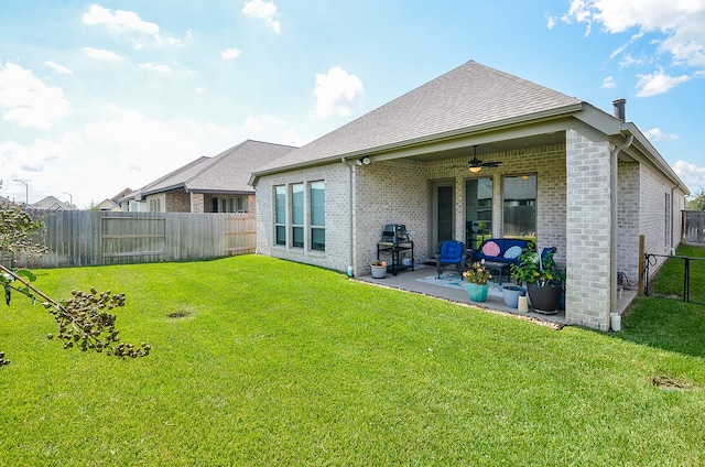 rear view of property featuring ceiling fan, a yard, and a patio area