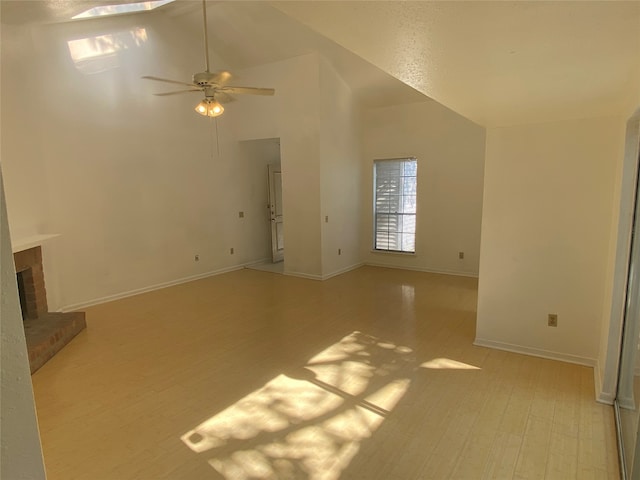 interior space featuring ceiling fan, a fireplace, light hardwood / wood-style floors, and high vaulted ceiling