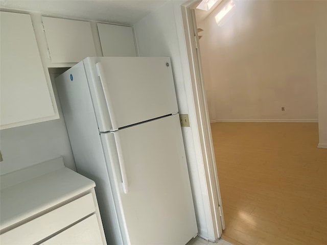 kitchen with white cabinetry, light hardwood / wood-style flooring, and white refrigerator