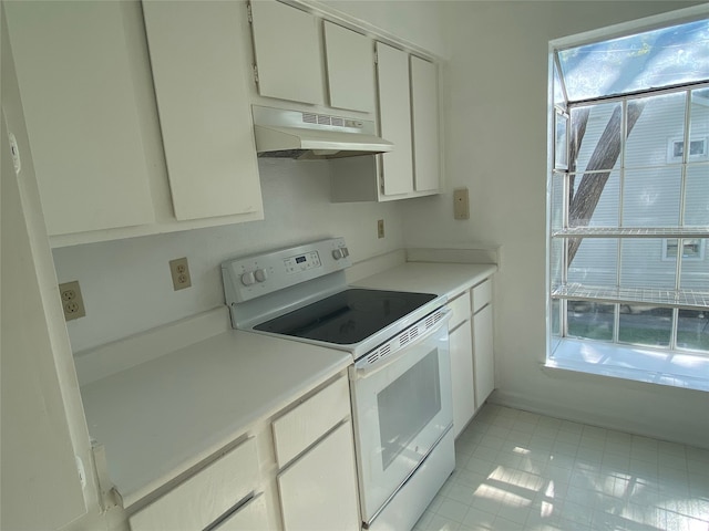 kitchen featuring light tile patterned floors, white cabinets, and white electric stove