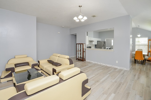 living room featuring light hardwood / wood-style flooring, a chandelier, and lofted ceiling