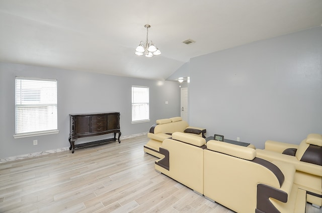 living room with light hardwood / wood-style flooring, a notable chandelier, lofted ceiling, and a healthy amount of sunlight