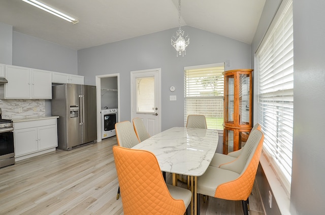 dining space featuring washer / clothes dryer, vaulted ceiling, an inviting chandelier, and light hardwood / wood-style flooring