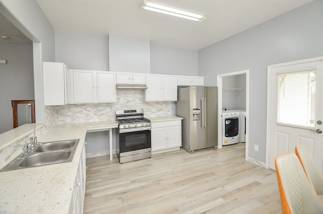 kitchen featuring light wood-type flooring, washer / clothes dryer, sink, decorative backsplash, and appliances with stainless steel finishes