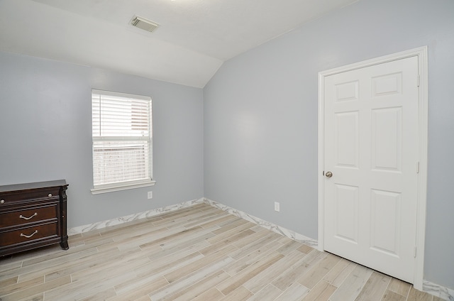 spare room featuring light hardwood / wood-style flooring and vaulted ceiling