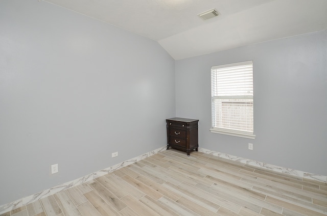 unfurnished room featuring light wood-type flooring and vaulted ceiling