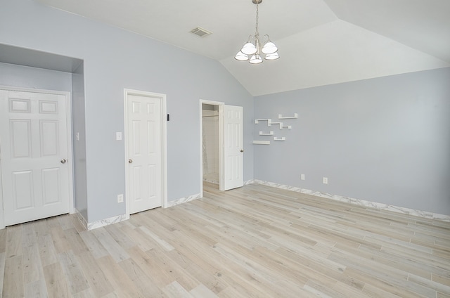 unfurnished bedroom featuring light hardwood / wood-style floors, vaulted ceiling, and an inviting chandelier