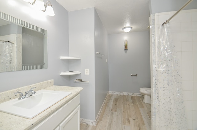 bathroom featuring walk in shower, hardwood / wood-style flooring, vanity, and toilet