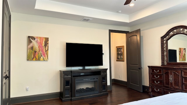 bedroom featuring dark hardwood / wood-style floors, ceiling fan, and a tray ceiling