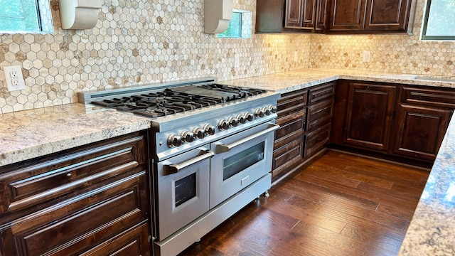 kitchen with dark brown cabinetry, tasteful backsplash, range with two ovens, and dark wood-type flooring