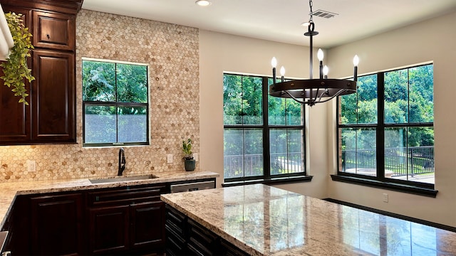 kitchen with hanging light fixtures, decorative backsplash, sink, and a wealth of natural light