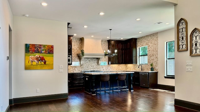 kitchen with a kitchen bar, dark hardwood / wood-style flooring, a kitchen island, and pendant lighting