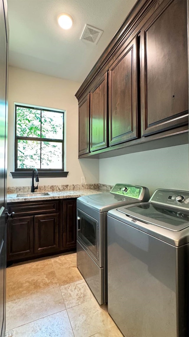 clothes washing area with washing machine and dryer, sink, and cabinets