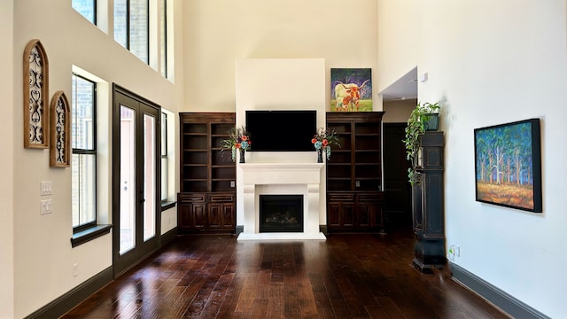 unfurnished living room with a high ceiling and dark wood-type flooring