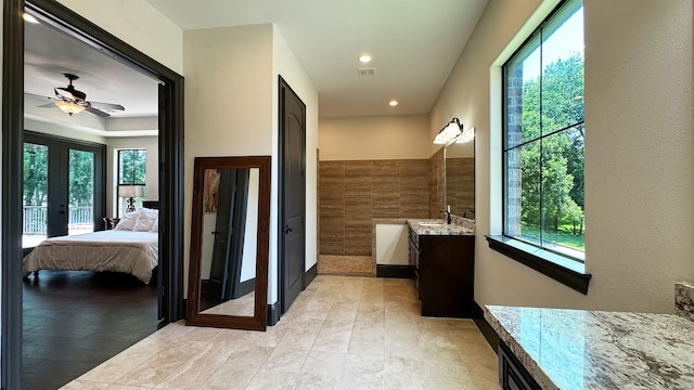 bathroom featuring plenty of natural light, ceiling fan, tile walls, and vanity