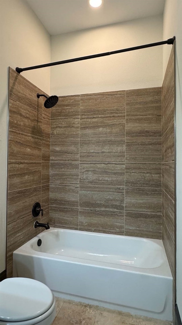 bathroom with tile patterned flooring, tiled shower / bath, and toilet