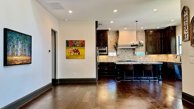 kitchen featuring a center island, a kitchen breakfast bar, dark hardwood / wood-style flooring, a notable chandelier, and pendant lighting