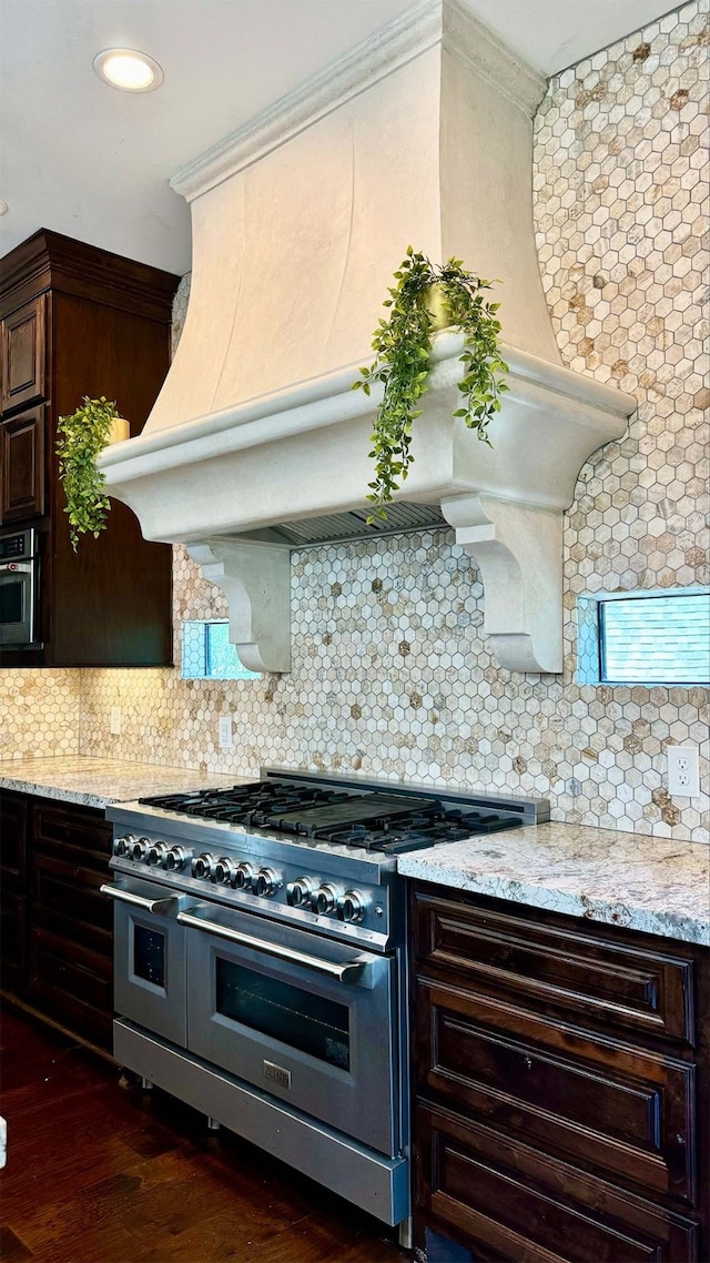 kitchen with backsplash, premium range hood, dark brown cabinetry, stainless steel appliances, and dark hardwood / wood-style floors