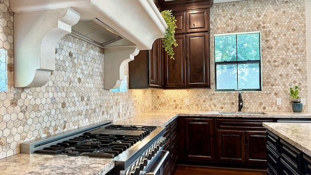 kitchen with sink, light stone counters, stainless steel range, tasteful backsplash, and dark hardwood / wood-style flooring