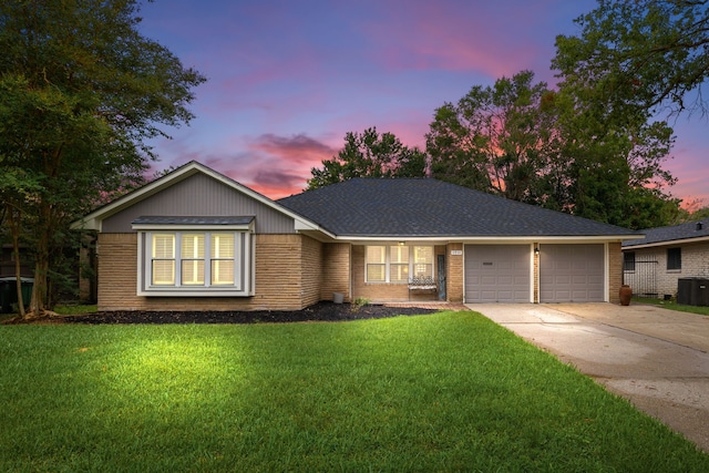 single story home with a yard, central AC unit, and a garage