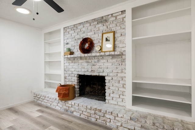 unfurnished living room featuring built in shelves, ornamental molding, a fireplace, a textured ceiling, and light hardwood / wood-style floors