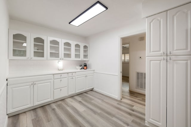 kitchen featuring white cabinets, light hardwood / wood-style floors, and tasteful backsplash