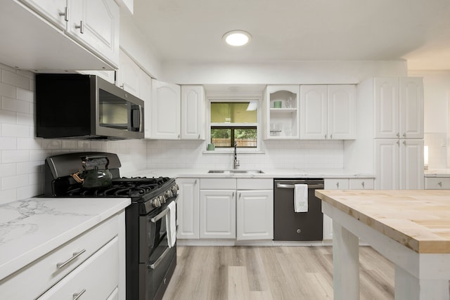 kitchen featuring tasteful backsplash, white cabinetry, light hardwood / wood-style flooring, and stainless steel appliances