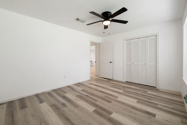 unfurnished bedroom featuring ceiling fan, a closet, and light wood-type flooring