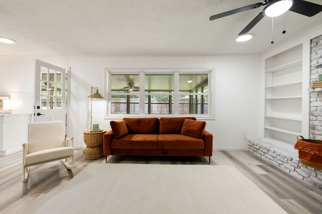 sitting room with built in features, light hardwood / wood-style flooring, and a textured ceiling