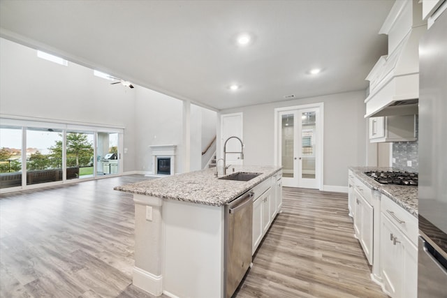 kitchen featuring white cabinetry, appliances with stainless steel finishes, sink, and a center island with sink