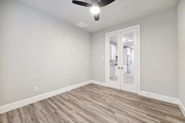 empty room with french doors, ceiling fan, and light hardwood / wood-style flooring