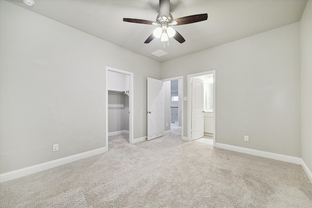 unfurnished bedroom with light colored carpet, connected bathroom, ceiling fan, a closet, and a spacious closet