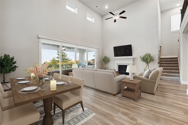 living room featuring a high ceiling, light wood-type flooring, and ceiling fan