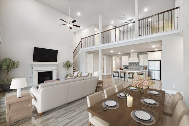 dining area featuring a high ceiling, ceiling fan, and light hardwood / wood-style floors