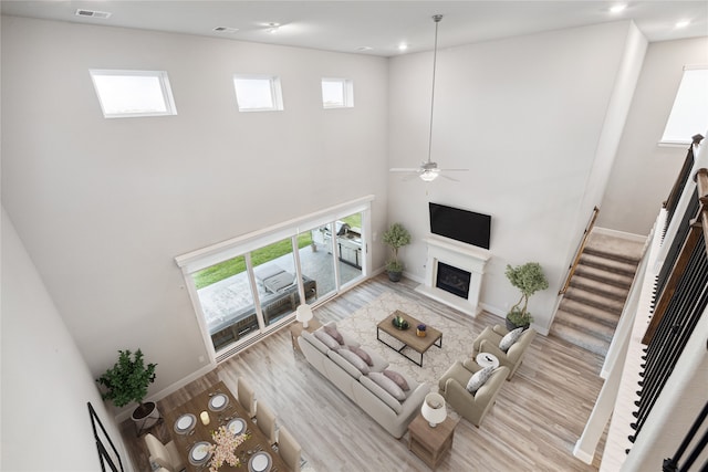 living room featuring a towering ceiling, a wealth of natural light, light hardwood / wood-style floors, and ceiling fan