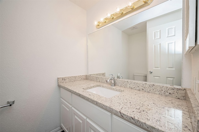 half bathroom with visible vents, vanity, and toilet