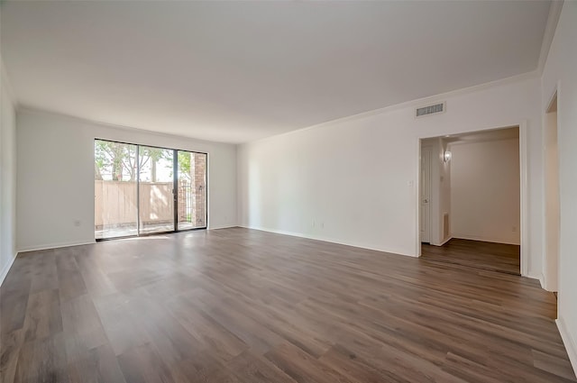 unfurnished room with baseboards, visible vents, dark wood-style floors, and crown molding